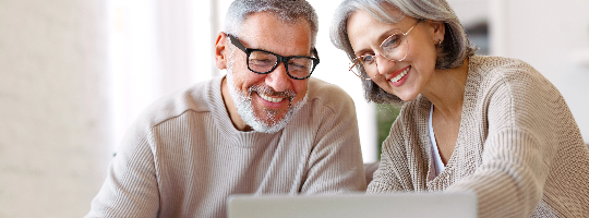 A man and a woman smiling at a laptop